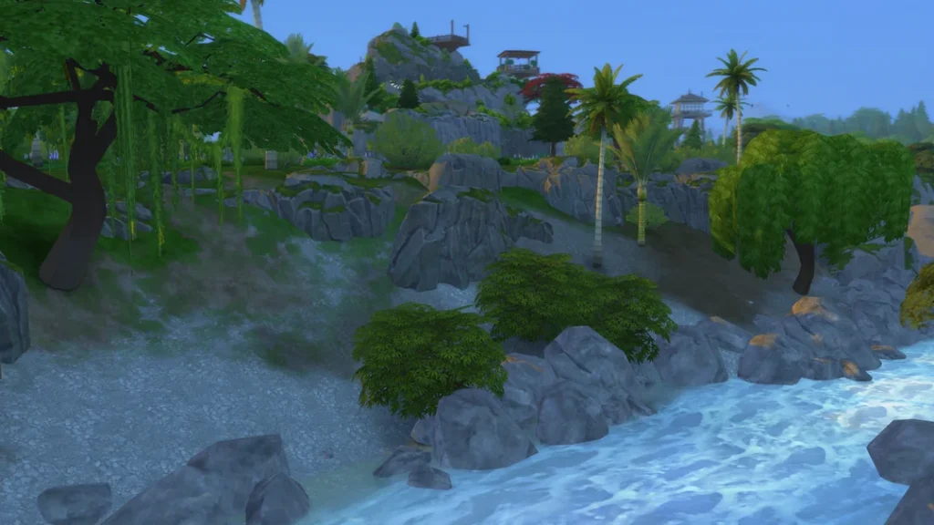 A coastal view of a custom explorable mountain build in The Sims 4, featuring rocky cliffs, layered paths, palm trees, dense greenery, and lookout structures above the shoreline.