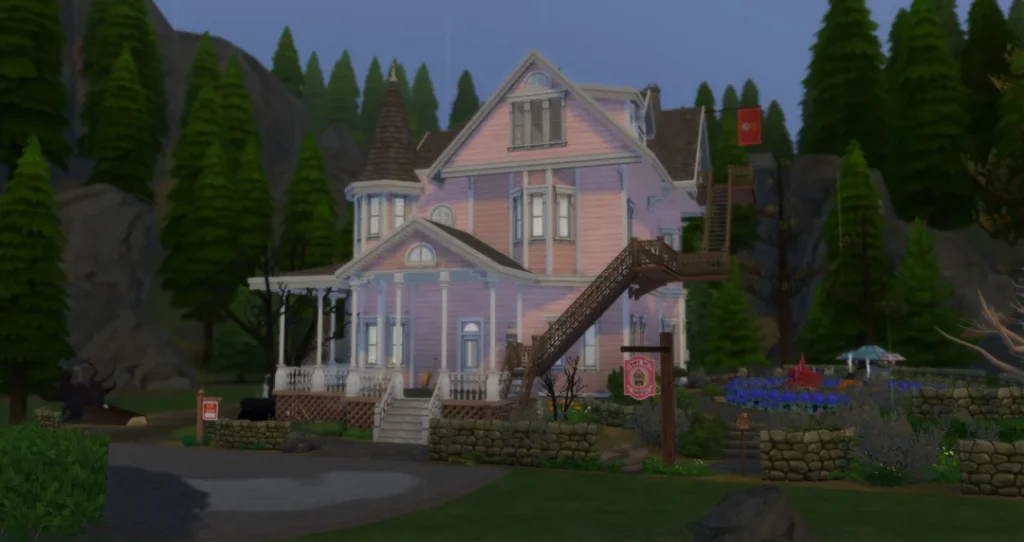 Exterior view of a detailed Pink Palace recreation in The Sims 4, inspired by Coraline, featuring a pastel pink Victorian house with a wraparound porch, turret, external staircase, stone garden walls, and forested mountain backdrop in Glimmerbrook.