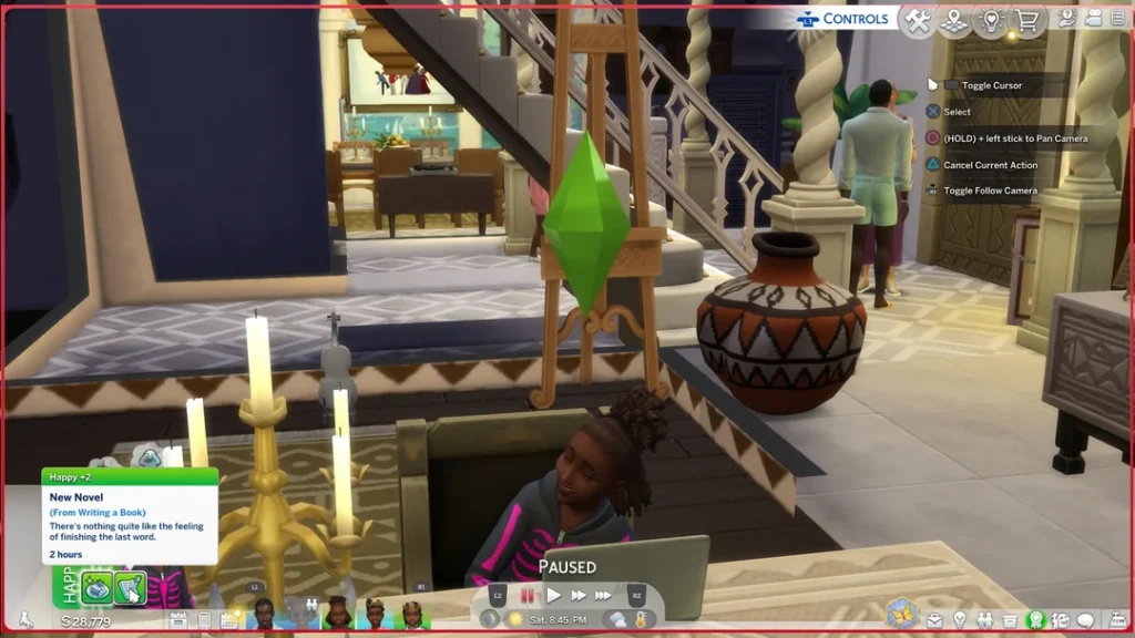 A Sims 4 gameplay screenshot showing a child Sim smiling while sitting at a desk with a laptop, candles nearby, and a home interior with stairs and another Sim in the background. The game is paused and a notification shows the child has finished writing a book.
